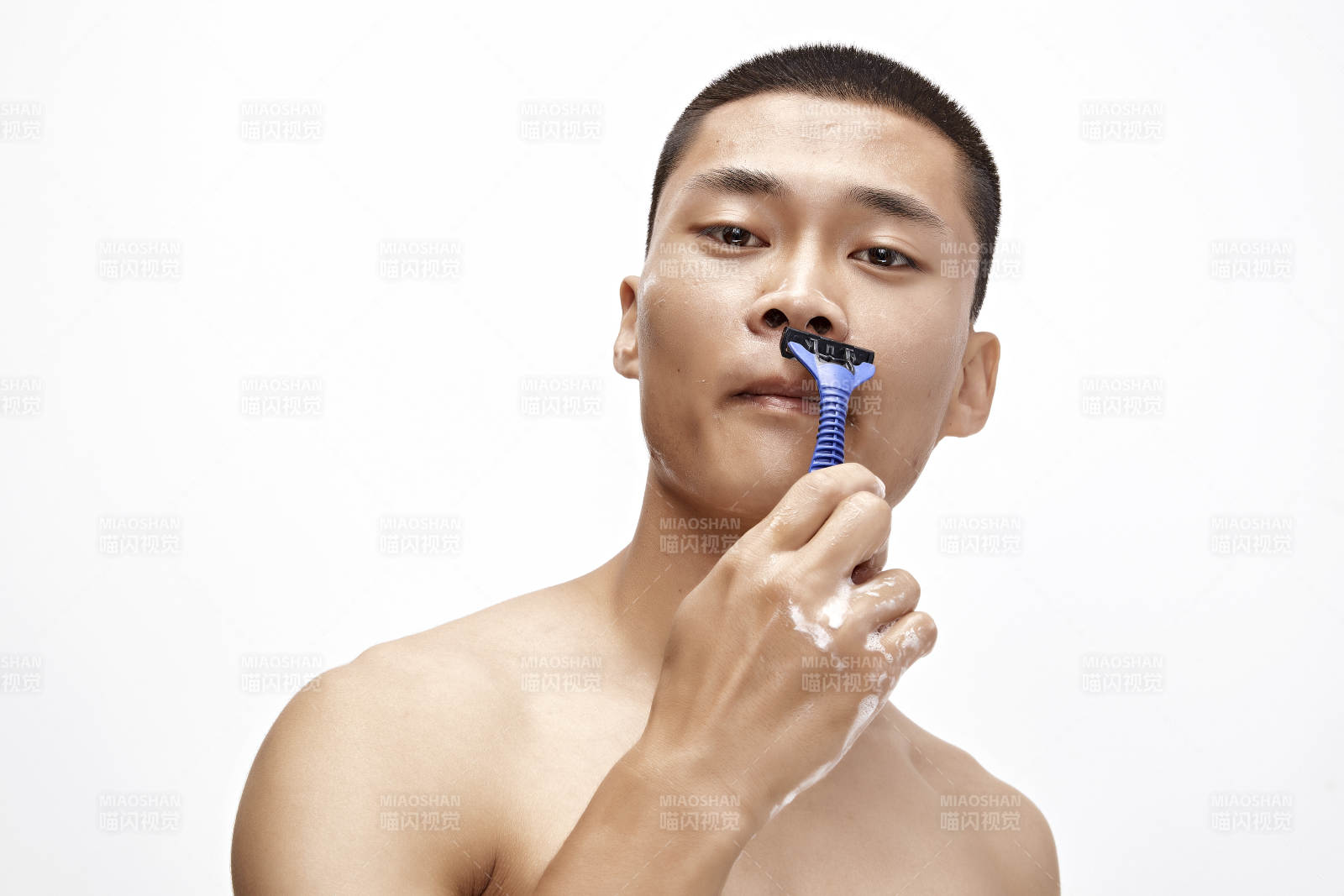 白色背景下手持剃须刀在刮胡子的亚洲男性图片
