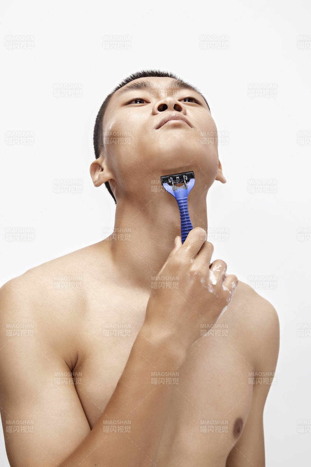 白色背景下手持剃须刀在刮胡子的亚洲男性图片