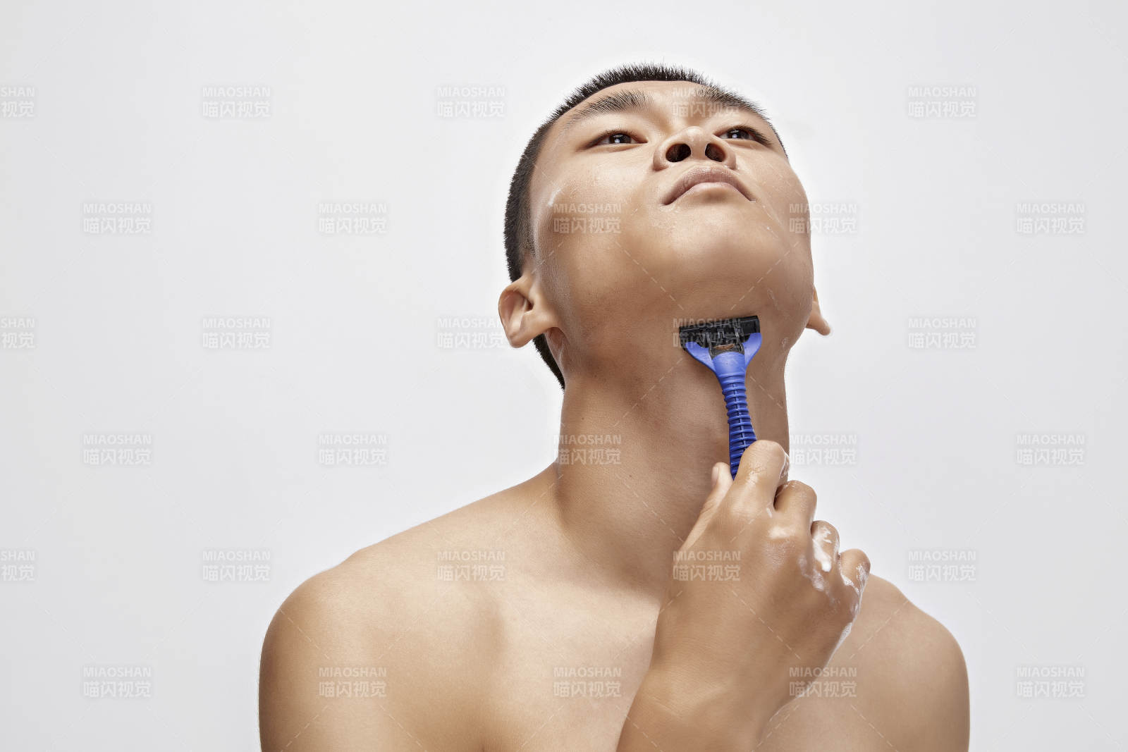 白色背景下手持剃须刀在刮胡子的亚洲男性图片