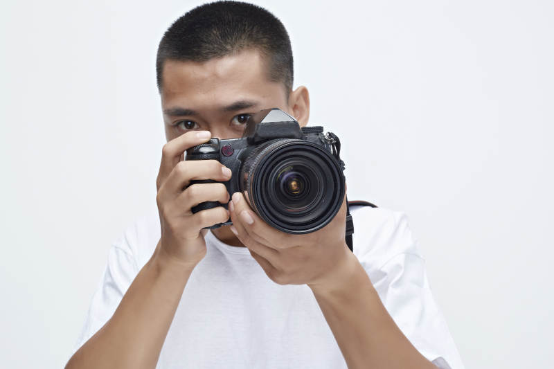 白色背景下手持照相机的亚洲男性摄影师图片