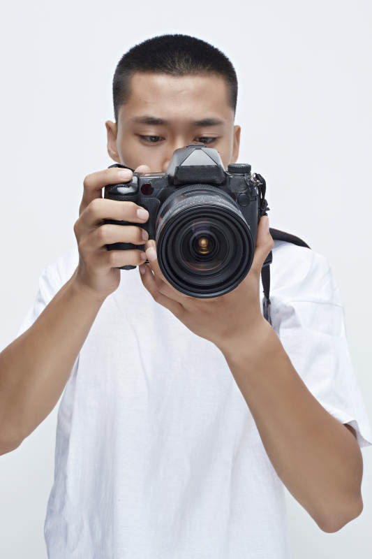 白色背景下手持照相机的亚洲男性摄影师图片