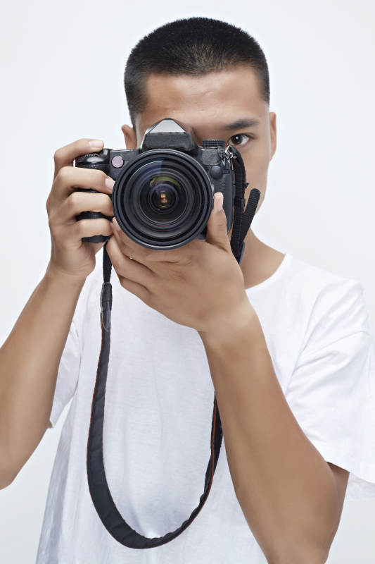 白色背景下手持照相机的亚洲男性摄影师图片