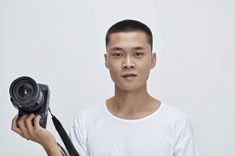 白色背景下手持照相机的亚洲男性摄影师图片