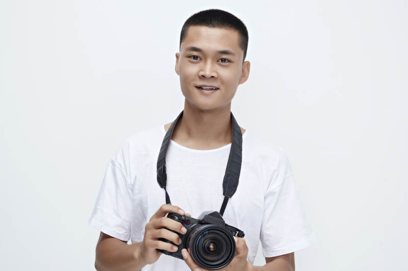白色背景下手持照相机的亚洲男性摄影师图片