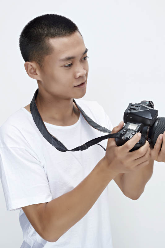 白色背景下手持照相机的亚洲男性摄影师图片