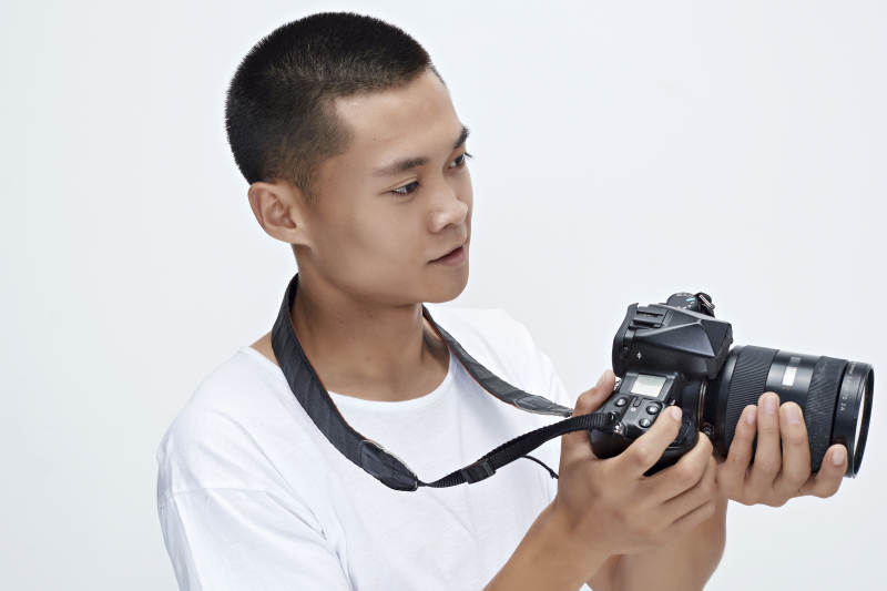 白色背景下手持照相机的亚洲男性摄影师图片