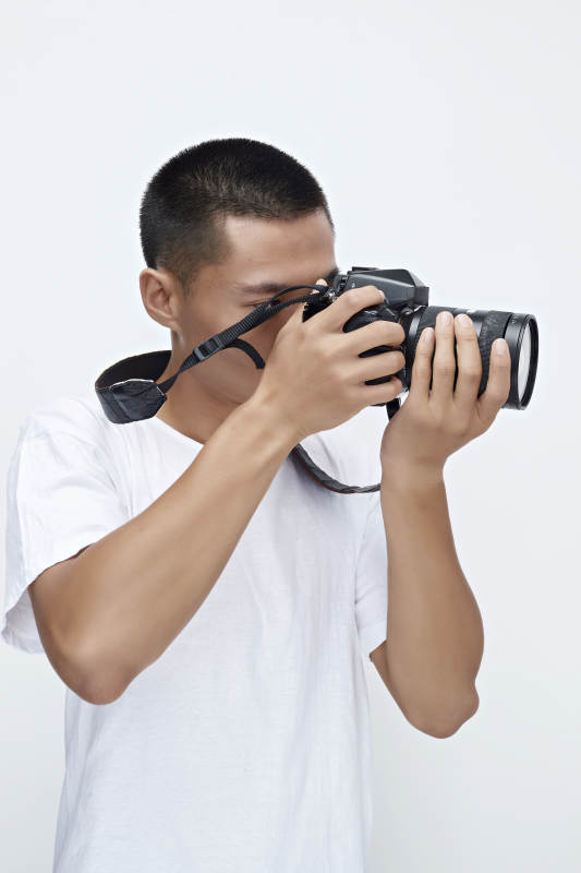 白色背景下手持照相机的亚洲男性摄影师图片