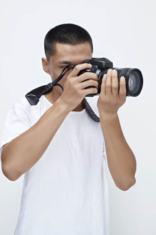 白色背景下手持照相机的亚洲男性摄影师图片