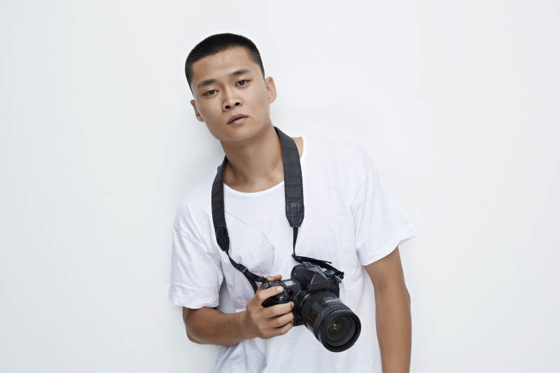 白色背景下手持照相机的亚洲男性摄影师图片