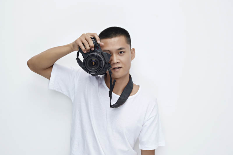 白色背景下手持照相机的亚洲男性摄影师图片