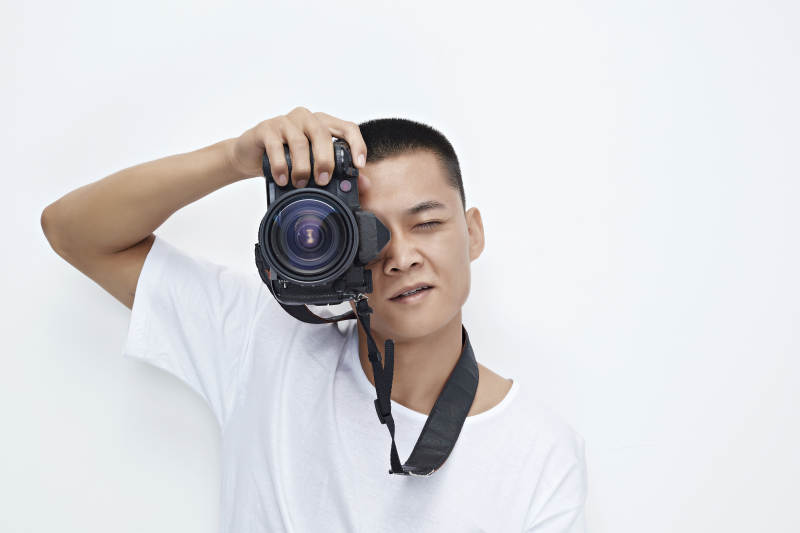 白色背景下手持照相机的亚洲男性摄影师图片