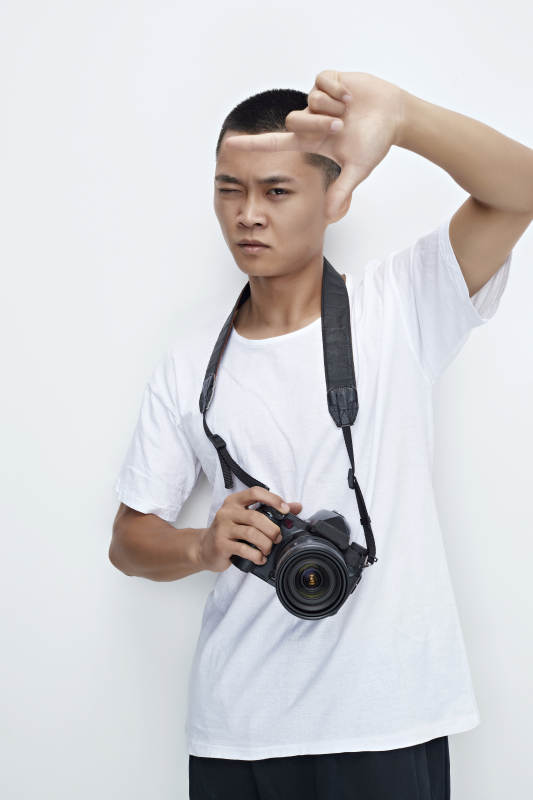 白色背景下手持照相机的亚洲男性摄影师图片