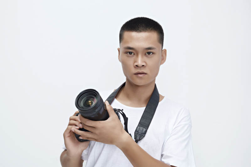 白色背景下手持照相机的亚洲男性摄影师图片