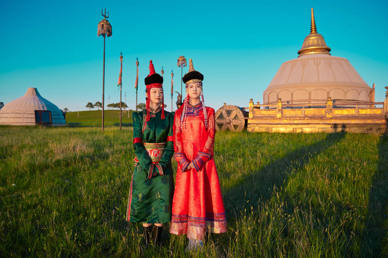 夕阳下草原蒙古大帐前穿蒙族服饰的美女图片