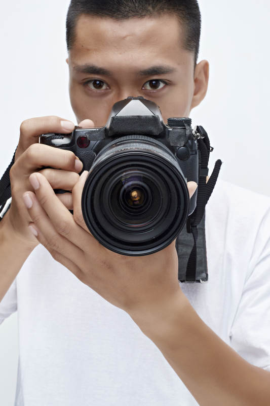 白色背景下手持照相机的亚洲男性摄影师图片