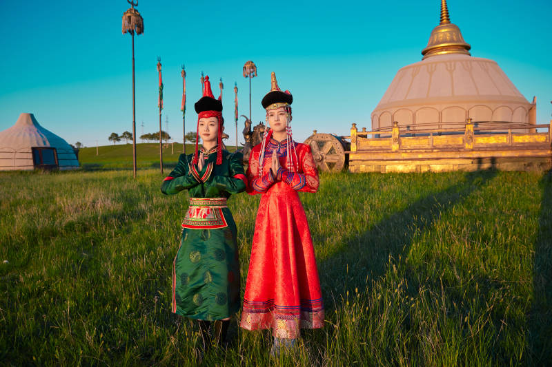 夕阳下草原蒙古大帐前穿蒙族服饰的美女图片
