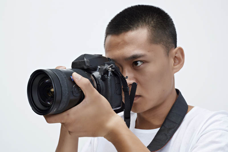 白色背景下手持照相机的亚洲男性摄影师图片