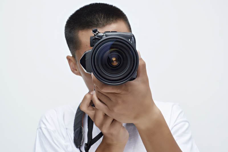 白色背景下手持照相机的亚洲男性摄影师图片