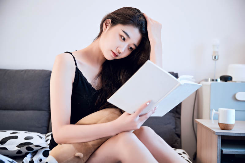 在床上阅读书籍的年轻女孩图片