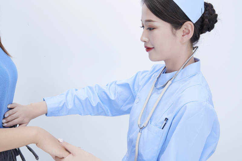 年轻的女性医护人员为患者进行身体按压检查图片