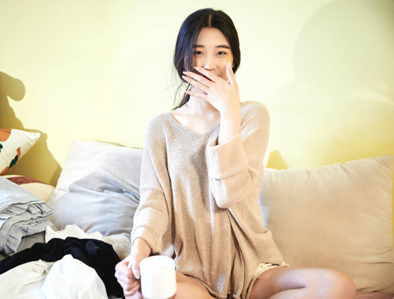 在沙发床上整理行装的年轻亚洲女性图片