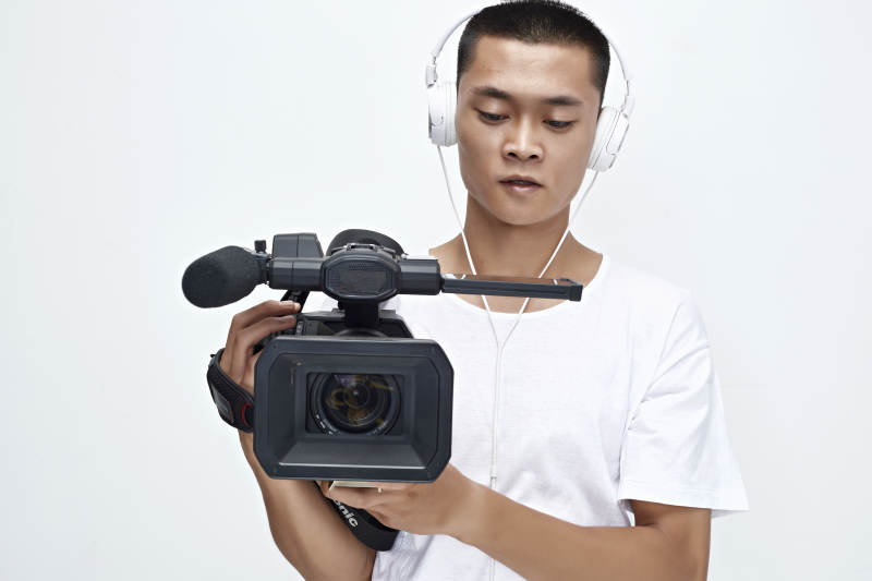 白色背景下手持摄像机进行录制拍摄的摄像师图片