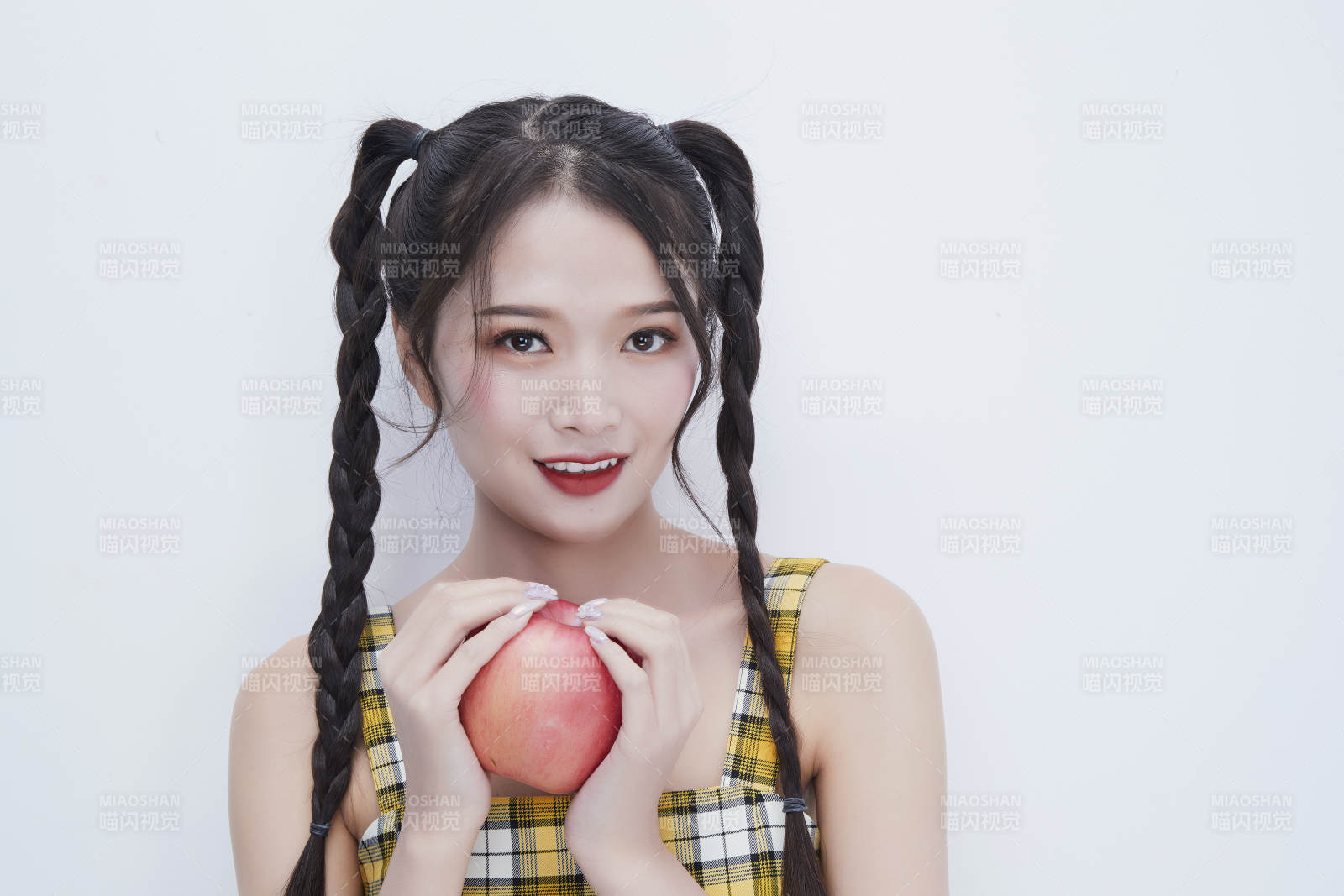 手拿苹果身穿格子吊带裙的亚洲可爱少女人像图片