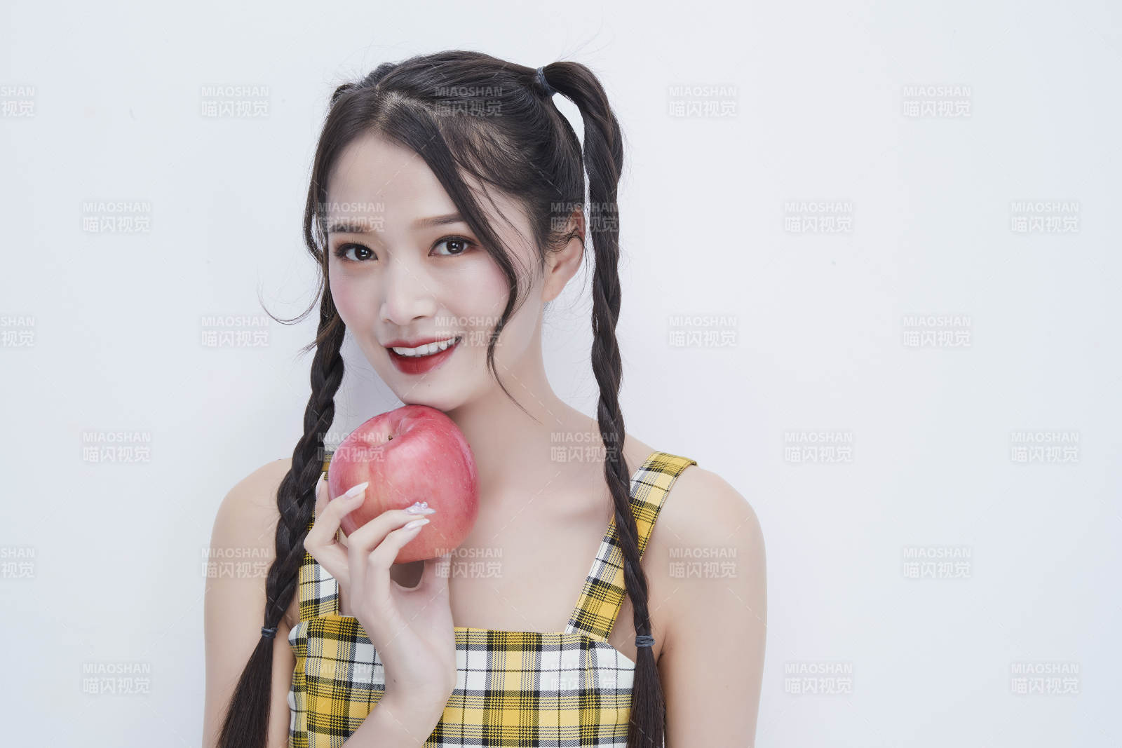 手拿苹果身穿格子吊带裙的亚洲可爱少女人像图片