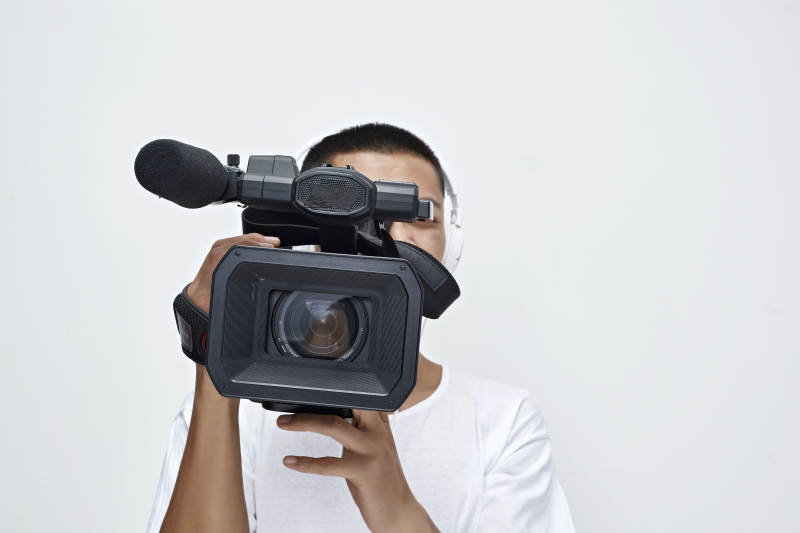 白色背景下手持摄像机进行录制拍摄的摄像师图片
