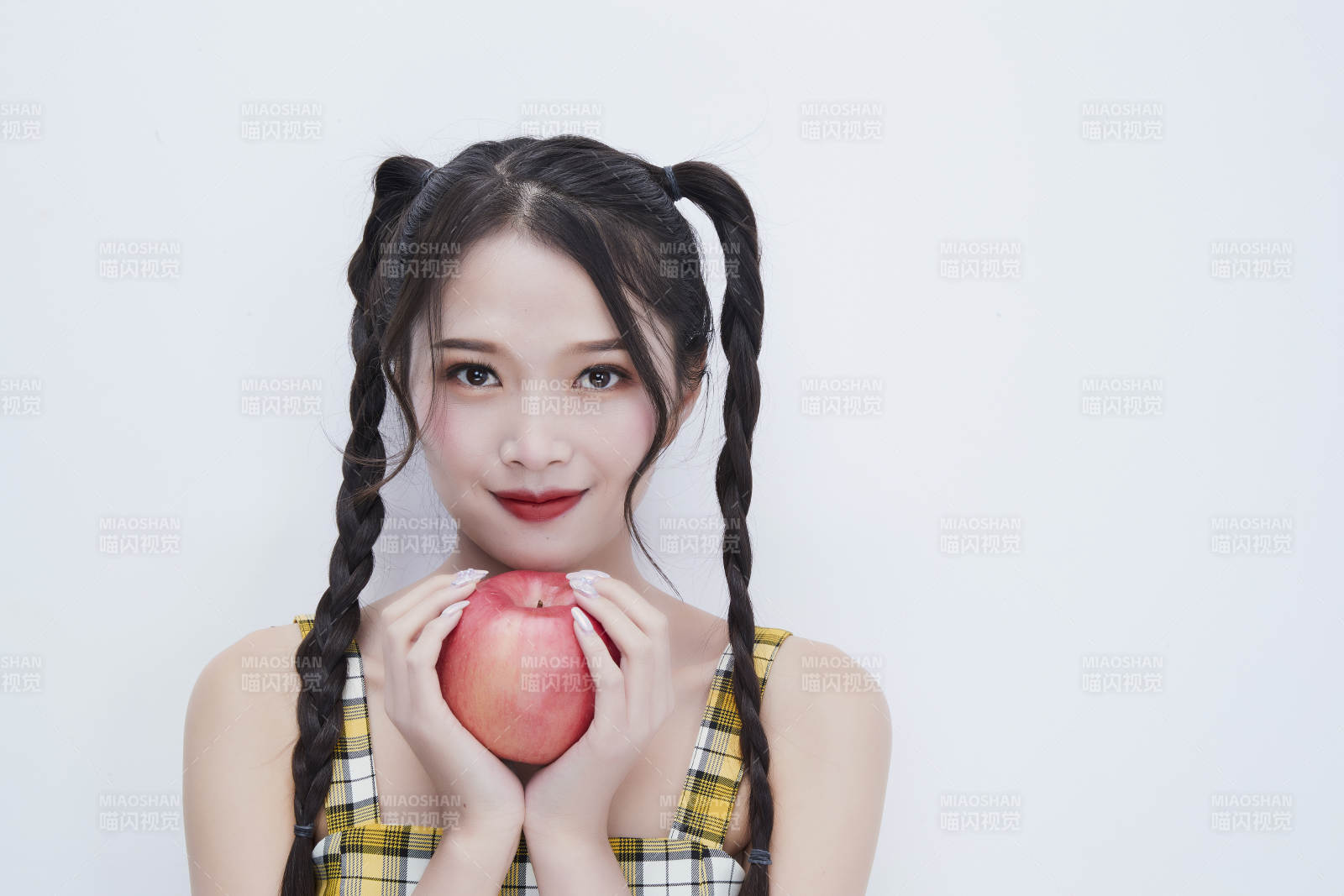 手拿苹果身穿格子吊带裙的亚洲可爱少女人像图片