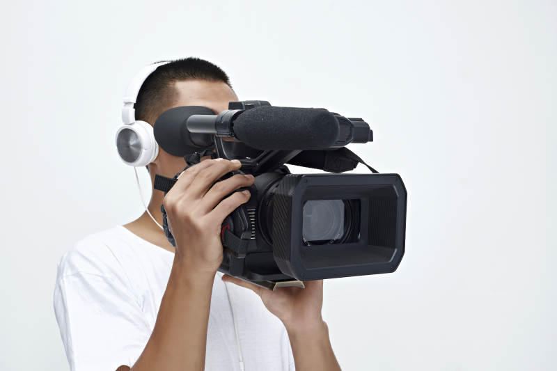 白色背景下手持摄像机进行录制拍摄的摄像师图片