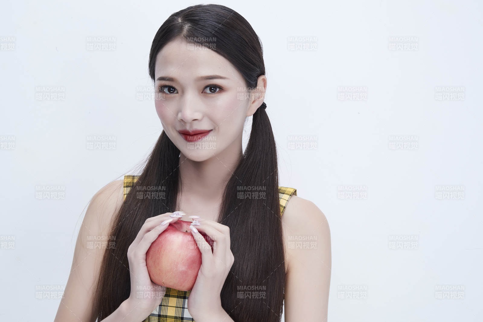 手拿苹果身穿格子吊带裙的亚洲可爱少女人像图片