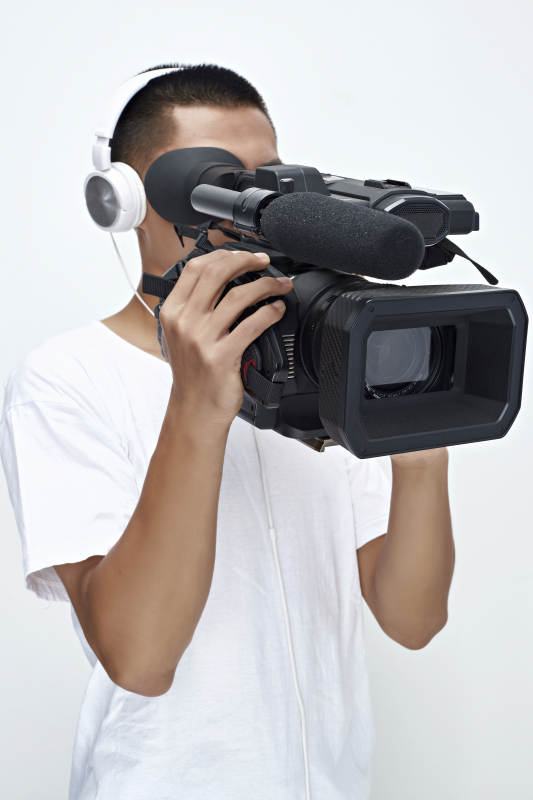 白色背景下手持摄像机进行录制拍摄的摄像师图片