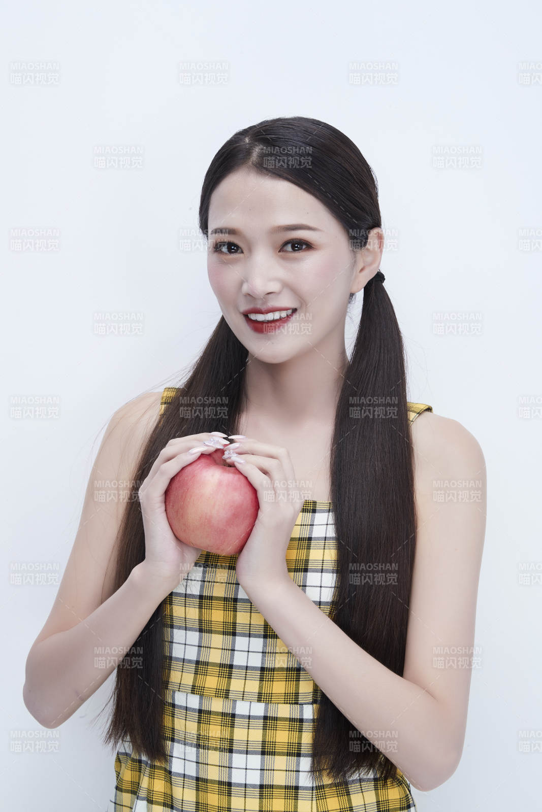 手拿苹果身穿格子吊带裙的亚洲可爱少女人像图片