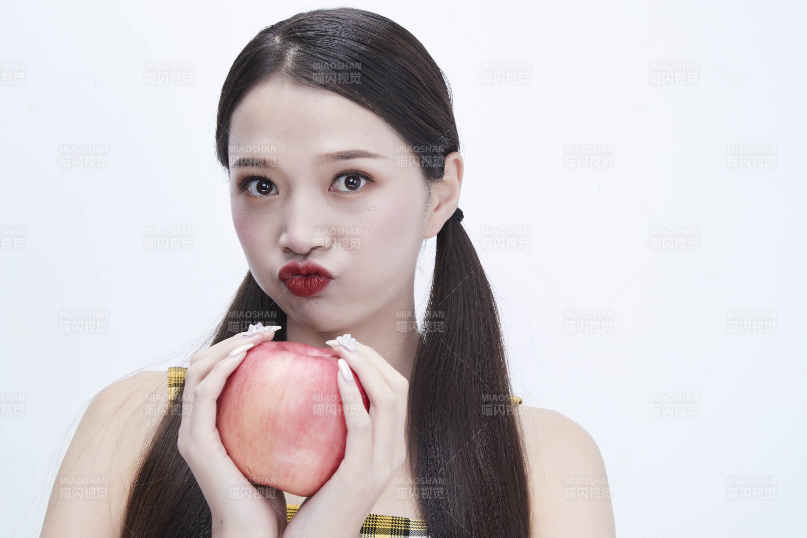 手拿苹果身穿格子吊带裙的亚洲可爱少女人像图片