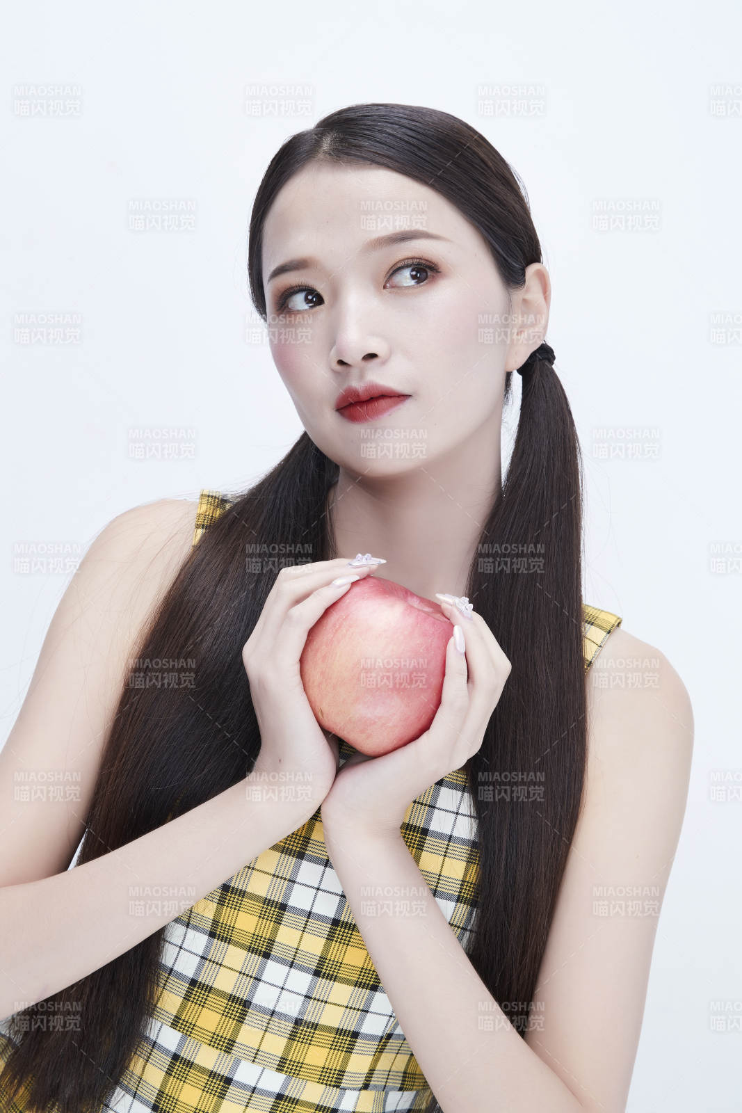 手拿苹果身穿格子吊带裙的亚洲可爱少女人像图片