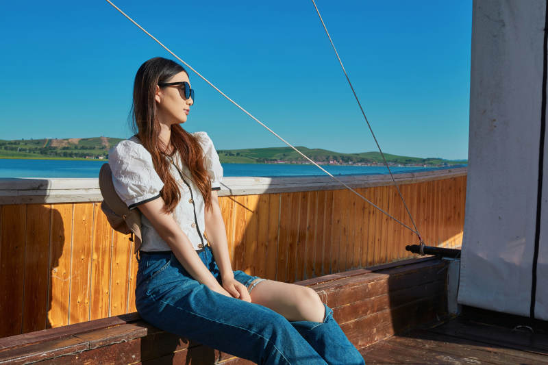 在湖畔木制帆船上的亚洲美女图片