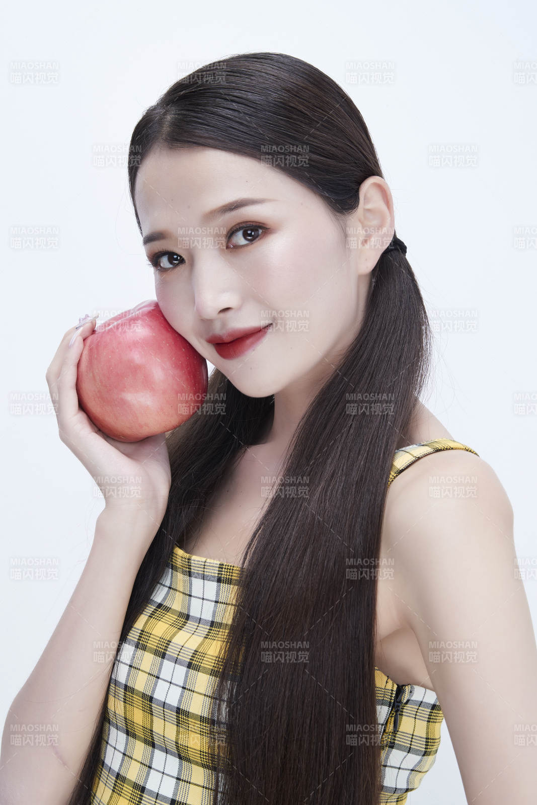 手拿苹果身穿格子吊带裙的亚洲可爱少女人像图片