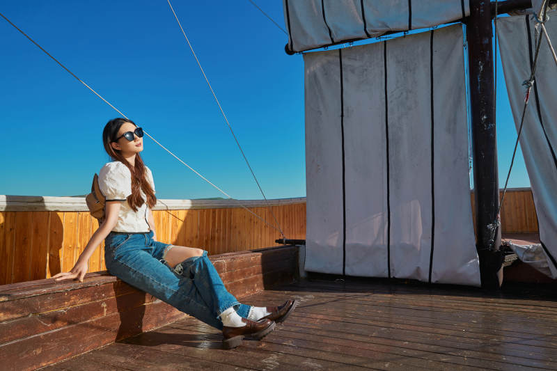 在湖畔木制帆船上的亚洲美女图片