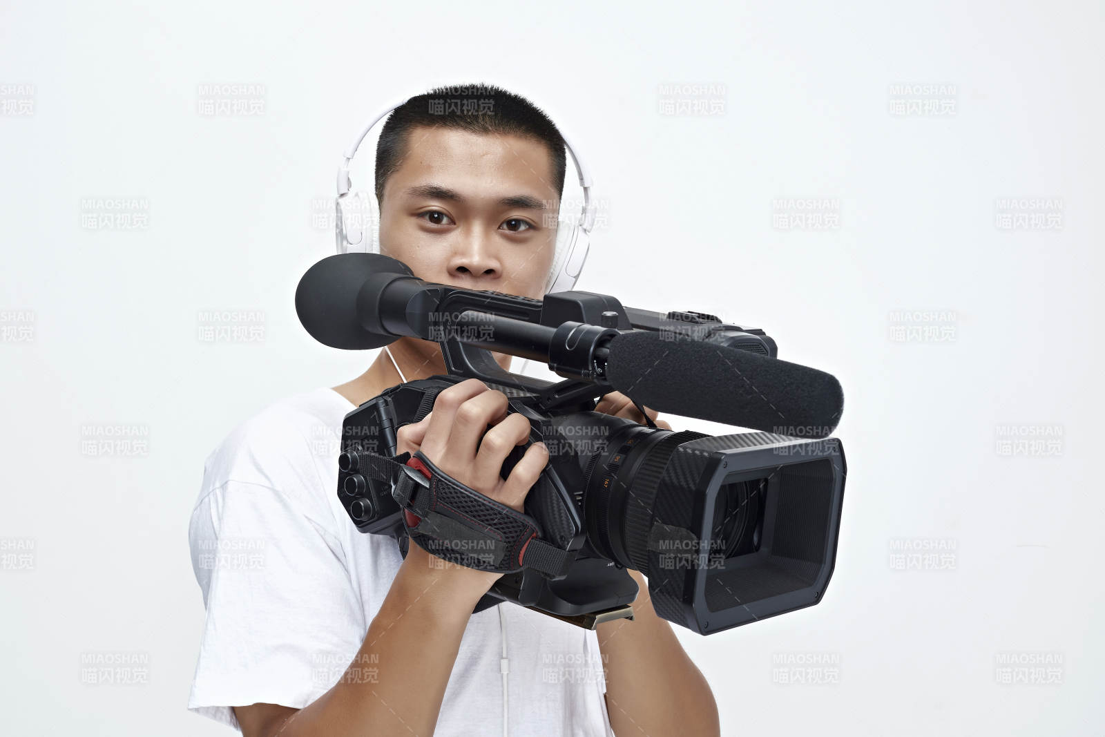 白色背景下手持摄像机进行录制拍摄的摄像师图片