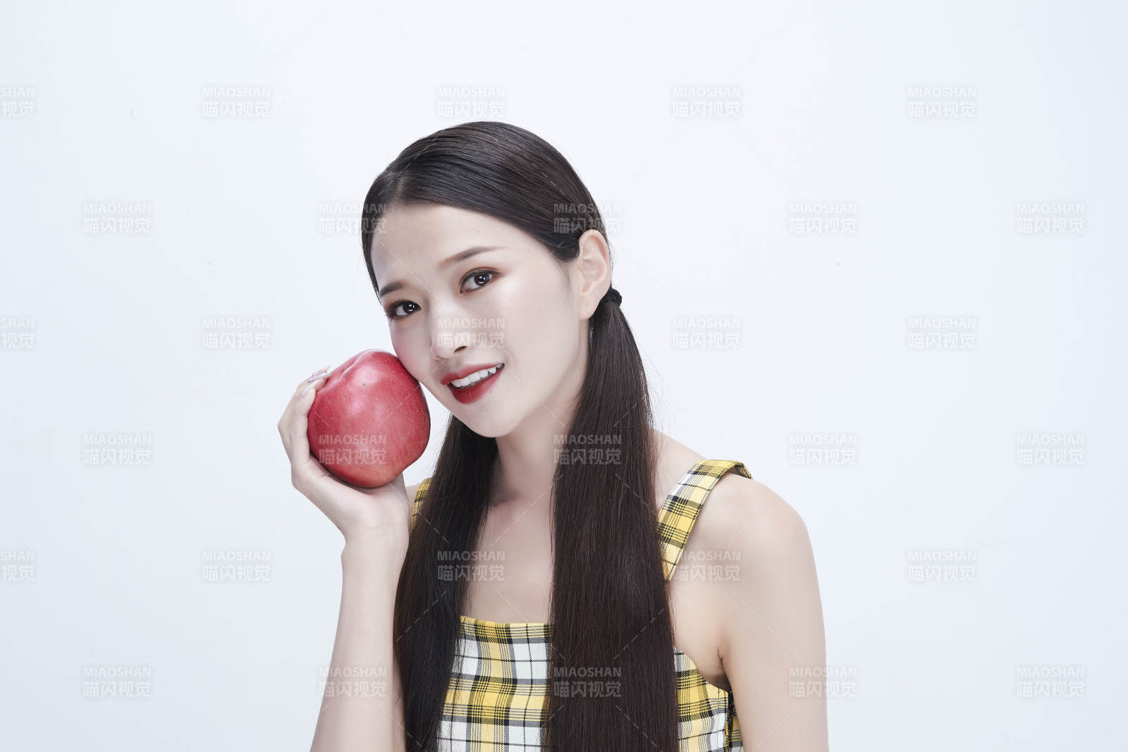 手拿苹果身穿格子吊带裙的亚洲可爱少女人像图片