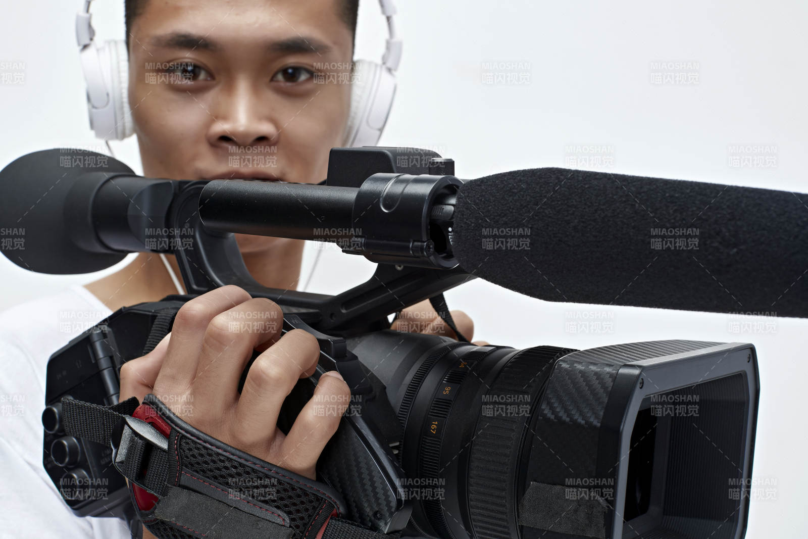 白色背景下手持摄像机进行录制拍摄的摄像师图片