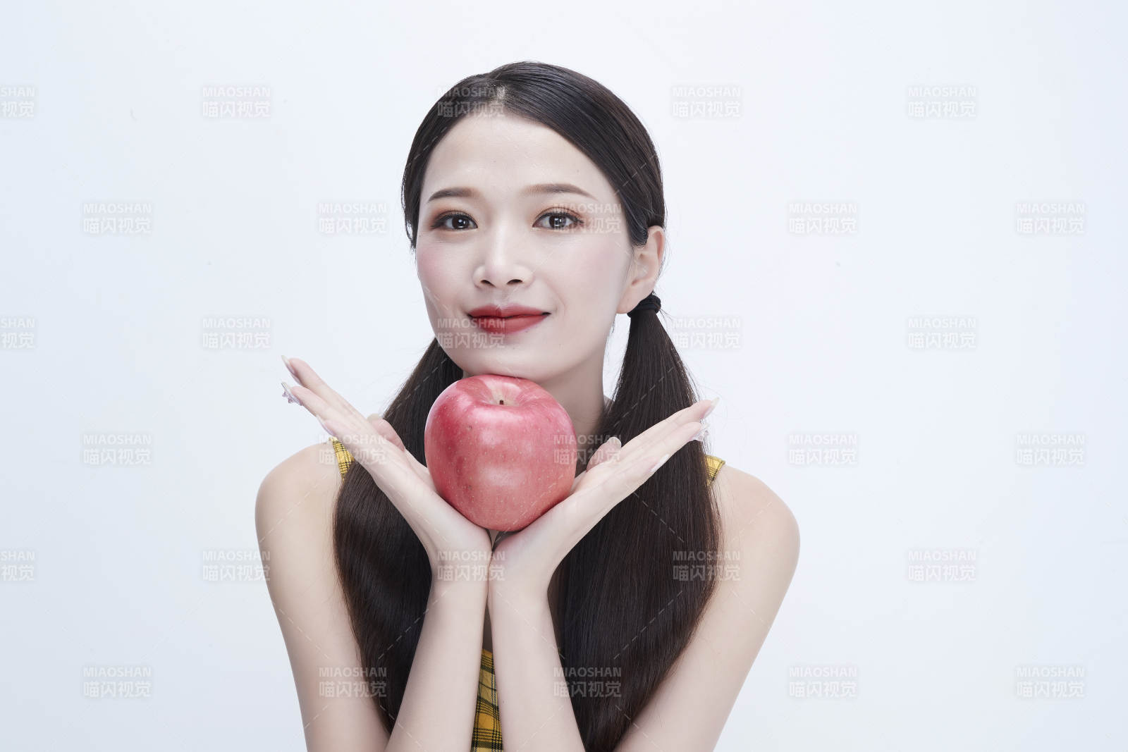 手拿苹果身穿格子吊带裙的亚洲可爱少女人像图片