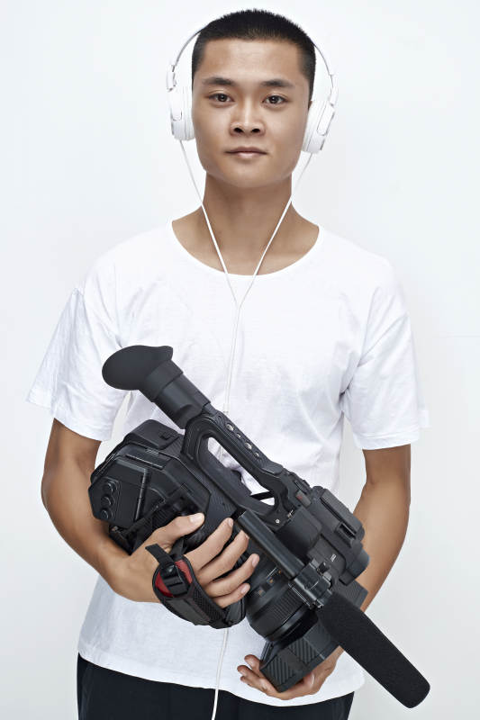 白色背景下手持摄像机进行录制拍摄的摄像师图片