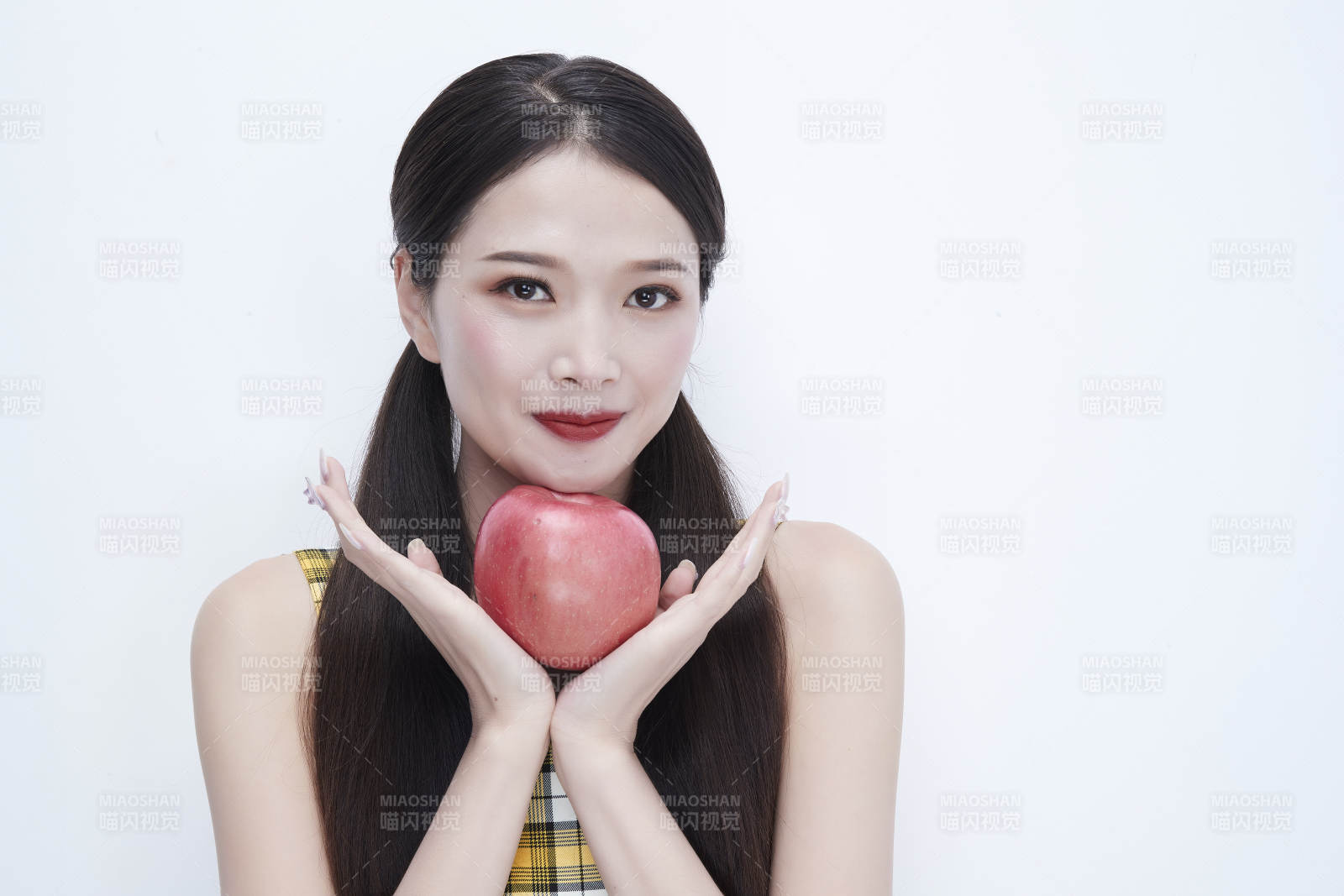 手拿苹果身穿格子吊带裙的亚洲可爱少女人像图片