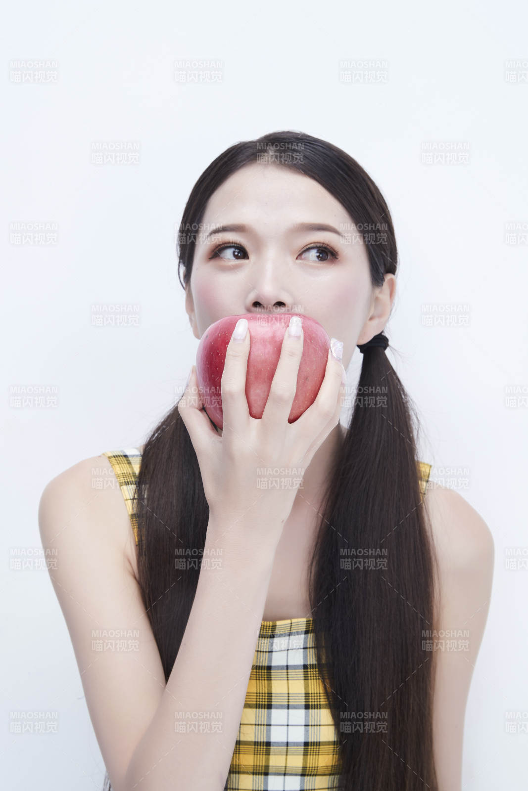 手拿苹果身穿格子吊带裙的亚洲可爱少女人像图片