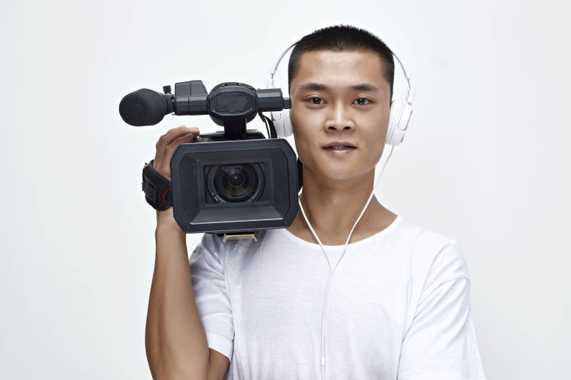 白色背景下手持摄像机进行录制拍摄的摄像师图片