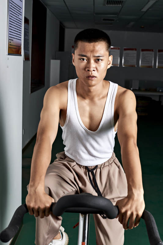 在室内进行动感单车锻炼的亚洲健身男士形象图片