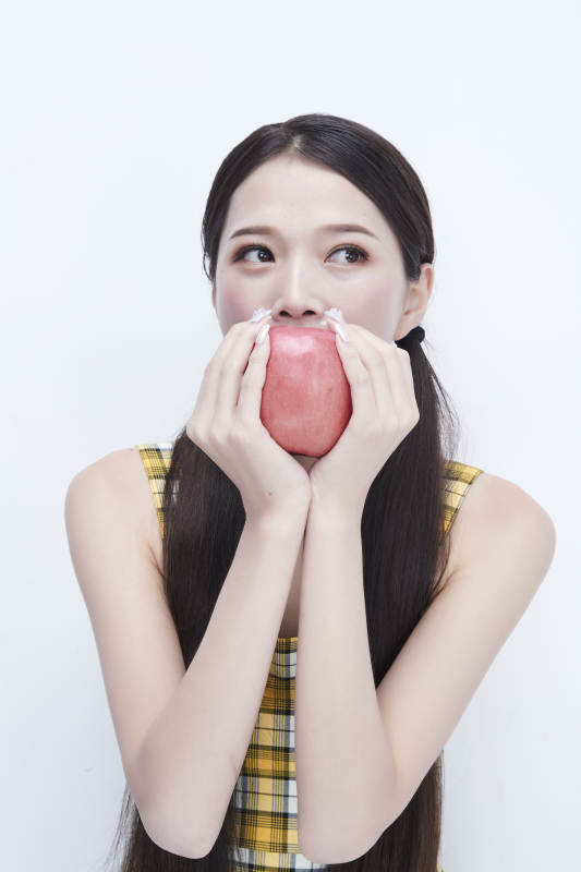 手拿苹果身穿格子吊带裙的亚洲可爱少女人像图片