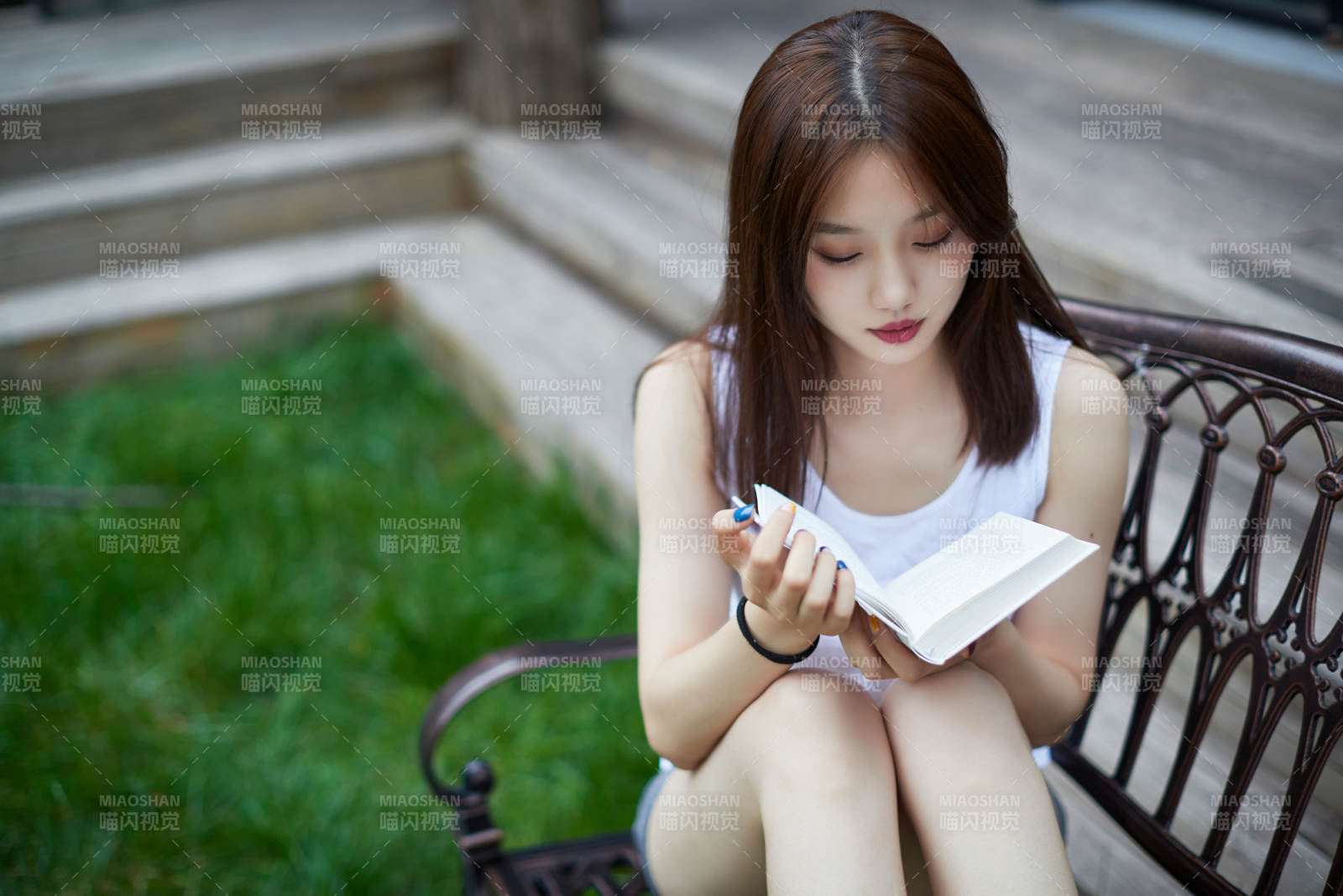 院子里坐在长椅上阅读书籍的亚洲长发少女图片